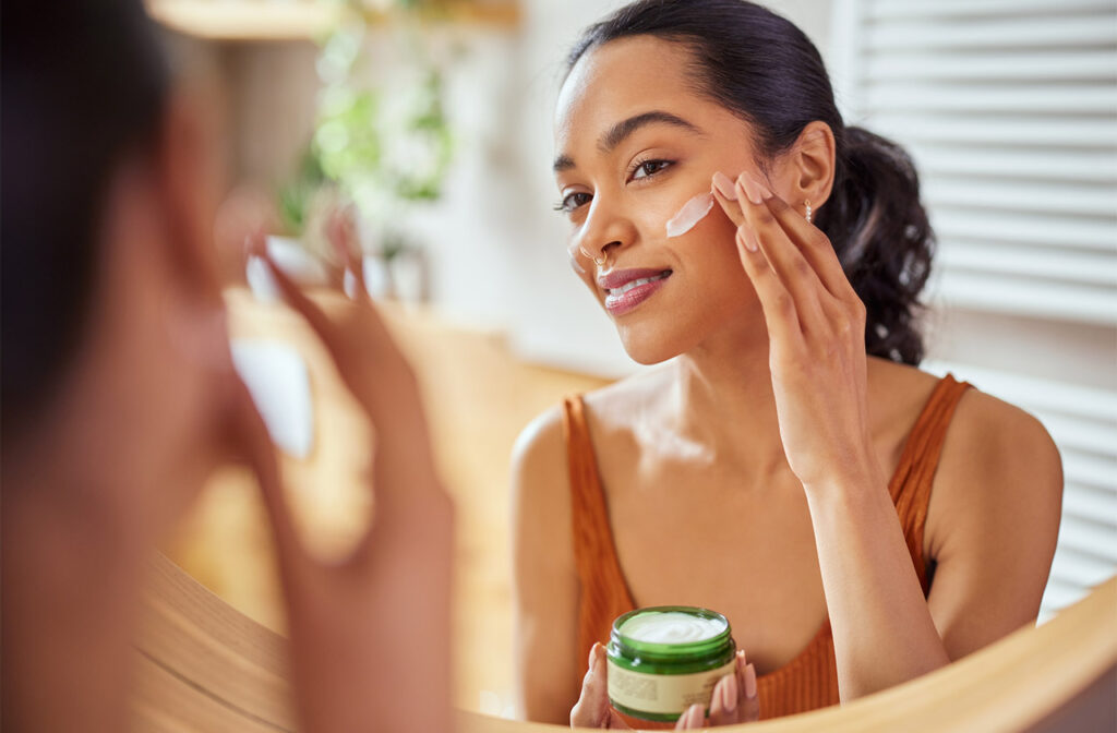 Woman applying cream to her face